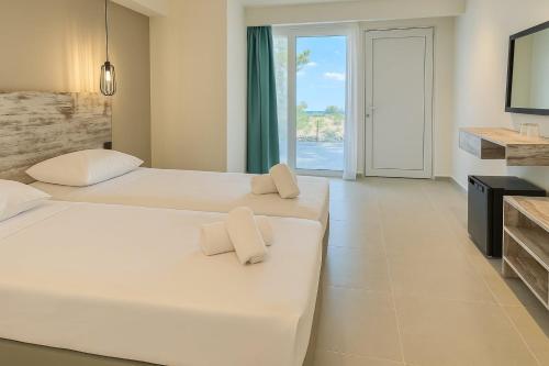 two beds in a hotel room with two towels at Evita Dream Hotel in Marmari