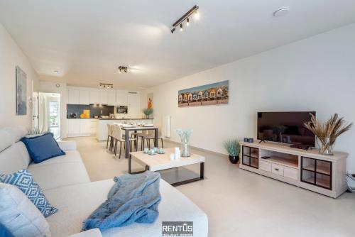 a living room with a white couch and a tv at Thyline One - new spacious apartment for 8 persons in Nieuwpoort