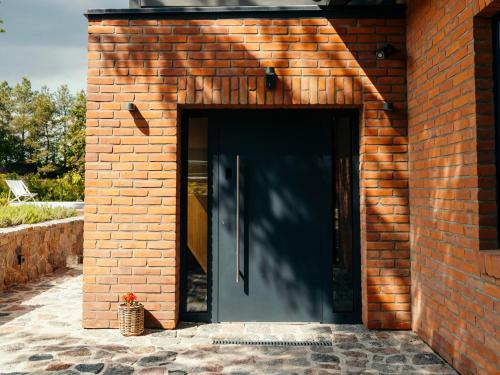 a brick building with a black door in it at Villa D'Jora in Mikołajki