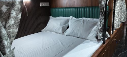 a bed with white pillows and a green headboard at Sunlight Dormitory in Mumbai