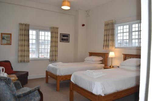 a hotel room with two beds and a chair at Royal Norfolk & Suffolk Yacht Club in Lowestoft