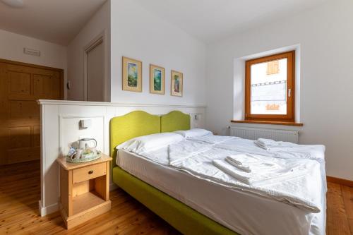 una camera da letto con un letto verde e bianco e una finestra di Alpedale a Ovaro