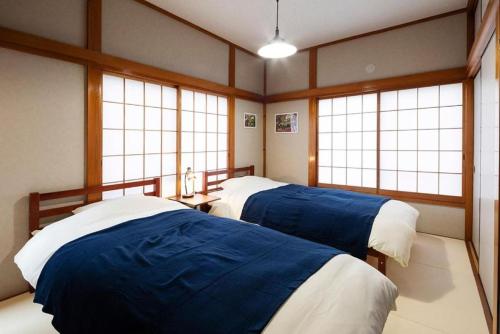 two beds in a room with three windows at Wave House Kujukuri Fujishita Near Kujukuri beach- Self Check-In Only in Kujukuri
