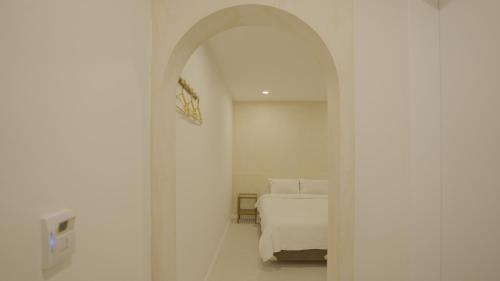 a white bedroom with a bed and an archway at Jeju Stay Hotel in Jeju