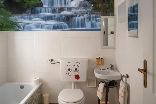 a bathroom with a toilet with a face drawn on the wall at La vista sul Castello in Cerreto