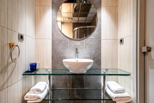 a bathroom with a sink and a mirror and towels at Comfy Boutique Hotel in Kalamata