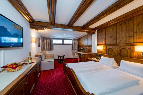 a hotel room with two beds and a television at Alpensporthotel Mutterberg in Mutterbergalm