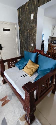 a wooden bed with blue and yellow pillows on it at Shanzu Beach Homes 105 in Mombasa