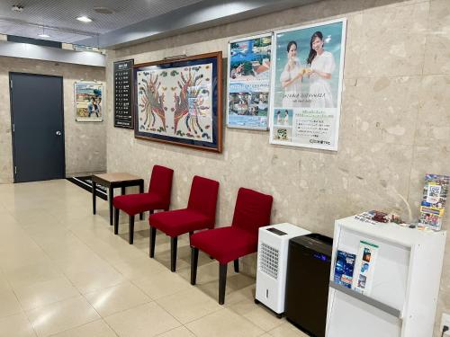 Ein Wartezimmer mit roten Stühlen und Postern an der Wand in der Unterkunft HOTEL LiVEMAX BUDGET Naha in Naha