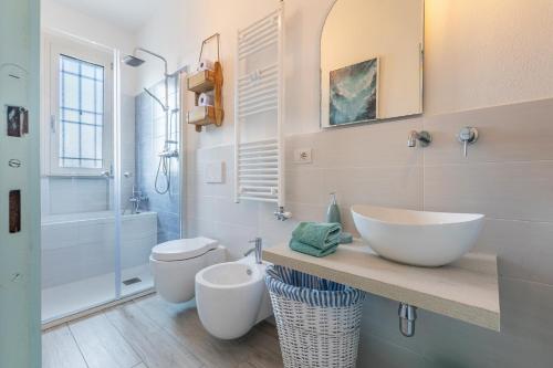 a white bathroom with a sink and a toilet at GuestHost - Parco del Sole Residence Flat with Terrace in lido degli scacchi