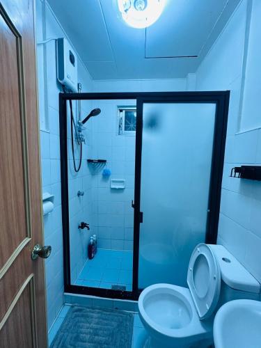 a bathroom with a toilet and a shower with a glass door at Oslob Cozy Home in Oslob