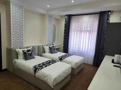 a hotel room with two beds and a window at SHOHI ZINDA Hotel in Samarkand
