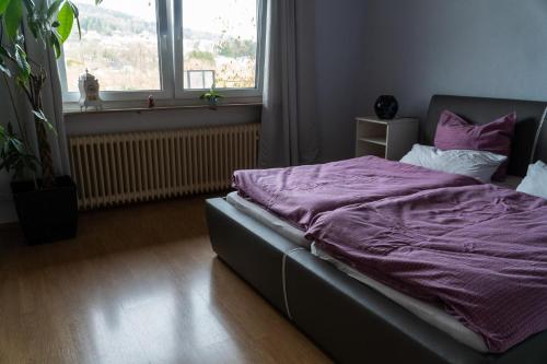 a bedroom with a bed with purple sheets and a window at Selina's Apartment in Oberthal
