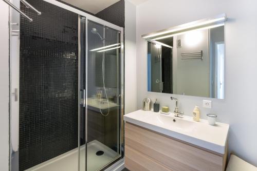 Un baño con ducha, lavabo y espejo. en Le Tregor by Cocoonr, en Rennes