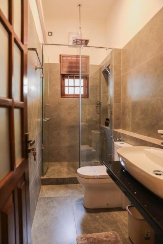 a bathroom with a toilet and a sink and a shower at Chamindu Villa Matara in Matara