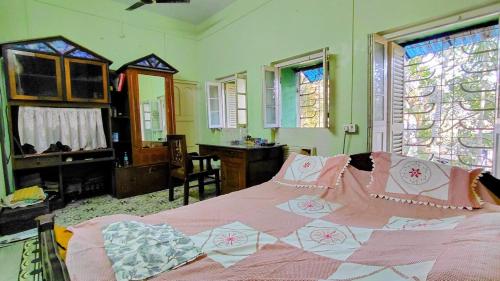 a bedroom with a bed and a desk and windows at Maya's Crest in Howrah
