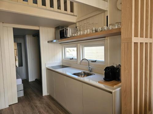 a small kitchen with a sink and a window at Skip Inn Strandhuisjes in Katwijk aan Zee