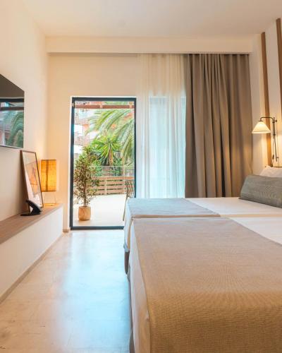 a hotel room with two beds and a sliding glass door at Ohtels Les Oliveres in Perelló