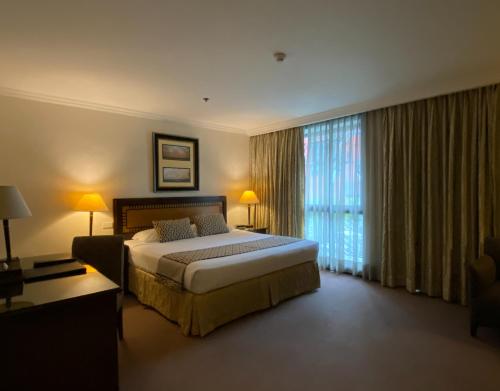 a bedroom with a large bed and a large window at Herald Suites Solana in Manila