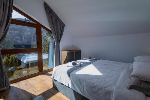 a bedroom with a bed and a large window at Nessa Chalet in Moara de Pădure