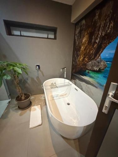 a bathroom with a white tub and a potted plant at Swanepoel Guesthouse in Jeffreys Bay