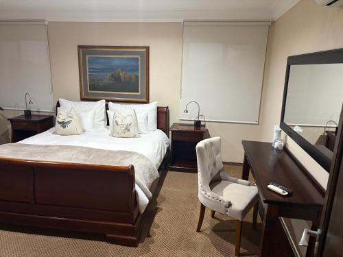 a hotel room with a bed and a desk and a television at Swanepoel Guesthouse in Jeffreys Bay