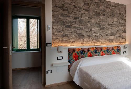 ein Schlafzimmer mit einem Bett und einer Steinwand in der Unterkunft Da Cuful in Reana del Roiale