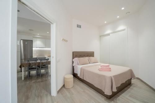 a white bedroom with a bed and a dining room at Mimi's Apartment in En Corts in Valencia