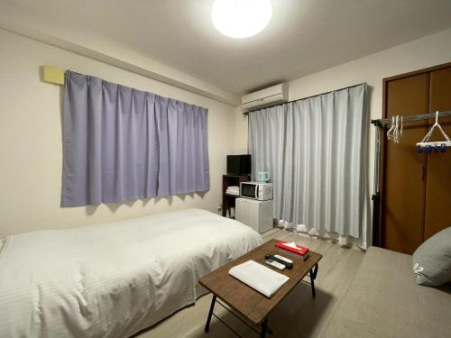 a hotel room with a bed and a table with a coffee table at マルチステイ大阪京橋 in Osaka