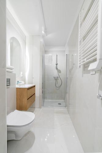 a white bathroom with a shower and a toilet at Luboń Urban Nest Studio by BookingHost in Luboń