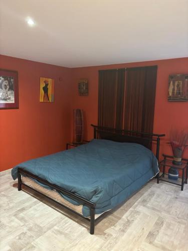 Un dormitorio con una cama en una habitación con paredes naranjas. en L'Estel, en Hasparren
