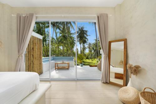 a bedroom with a bed and a balcony with a mirror at Baan Boho Villas in Ko Phangan