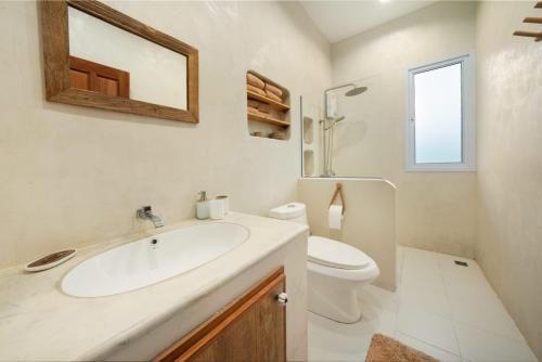 a bathroom with a sink and a toilet and a mirror at Baan Boho Villas in Ko Phangan