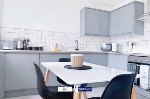 a white kitchen with a white table and chairs at Luxury two bedroom apartment with parking games and fast unlimited Wi-Fi by Hush Haven Homes Serviced Accommodation in Hull