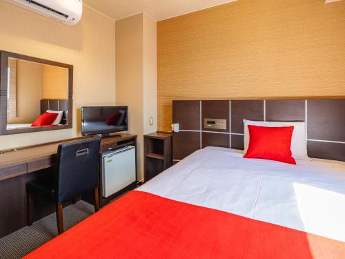 a bedroom with a bed and a desk with a red pillow at MyHotel Okazaki in Okazaki