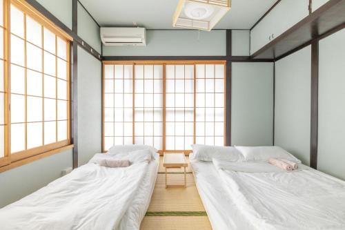 two beds in a room with two windows at Jazz Cat- Japanese Style House, 1Min to sta- 5 Lines Access- Direct to Shinjuku & Shibuya&Akihabara in Tokyo