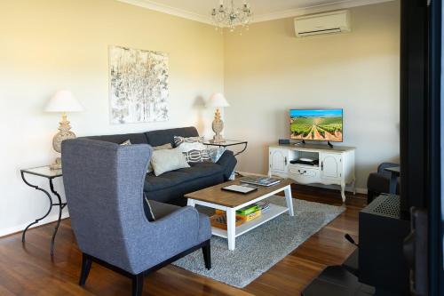 a living room with a blue couch and a tv at Red Door Collective - RDC Vineyard Estate, Luxury Adult Only Stay in Pokolbin