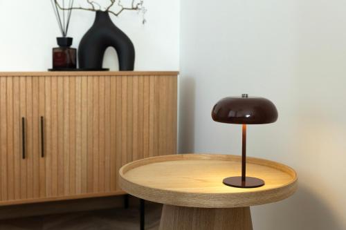 a wooden table with a brown lamp on top of it at ATRIUM City Center Apartment in Kaunas