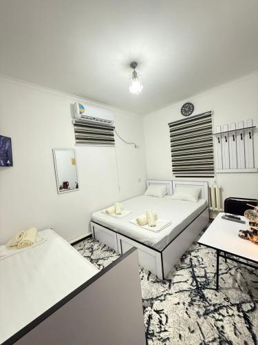 a white room with two beds and two tables at SumayShakh Guest House in Bukhara