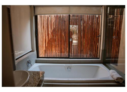a bathroom with a bath tub and a sink at Elements Private Golf Villa 295 in Warmbaths