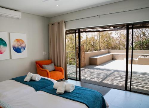 a bedroom with a large bed and an orange chair at Elements Private Golf Villa 295 in Warmbaths