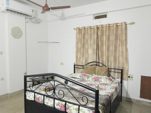 a bed in a room with a ceiling fan at Alice's Cozy Abode in Udupi
