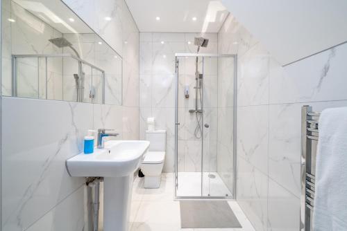 a white bathroom with a sink and a shower at Exquisite 4Bedroom House 4 Contractors & Large Families with Private Garden, Fully Equipped Kitchen and Close Proximity to Train & Bus Stations in Finchley