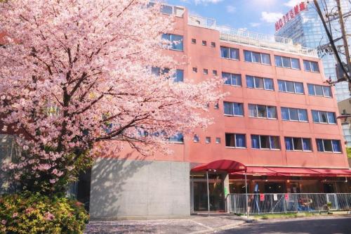 a pink flowering tree in front of a building at Sakura Hostel Asakusa in Tokyo