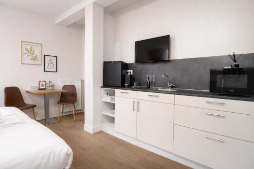a white kitchen with a sink and a tv at King's Inn City Hotel Alkmaar in Alkmaar