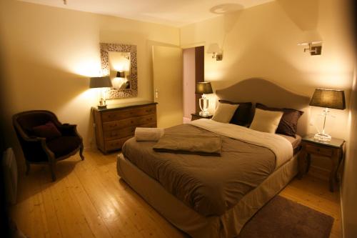 - une chambre avec un grand lit et une chaise dans l'établissement Maisons du Périgord Côté Vézère, à Terrasson