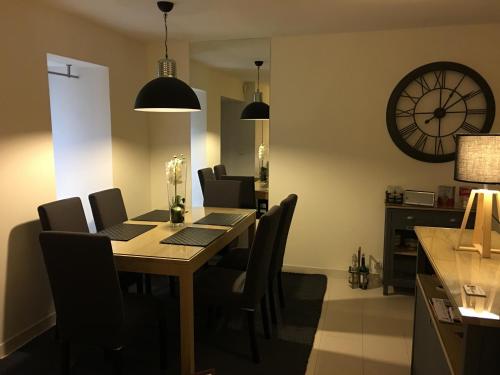 a dining room table with chairs and a clock on the wall at Maisons du Périgord Côté Vézère in Terrasson-Lavilledieu