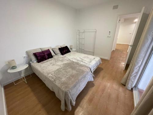 a white bedroom with a large bed and a table at Apartamento Pla in Girona