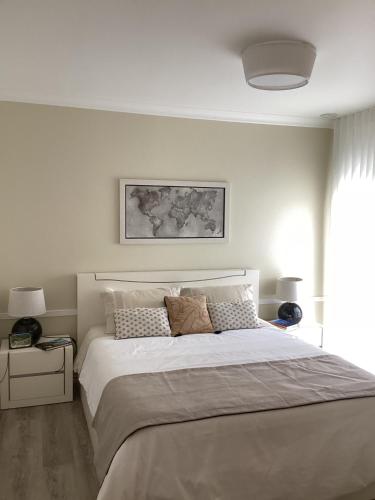 a white bedroom with a large bed and a window at Modern room (with deck) in Povoação