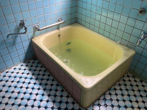 a bath tub in a bathroom with blue tiles at Family Homestay Shirokuro Guesthouse in Nakakiri